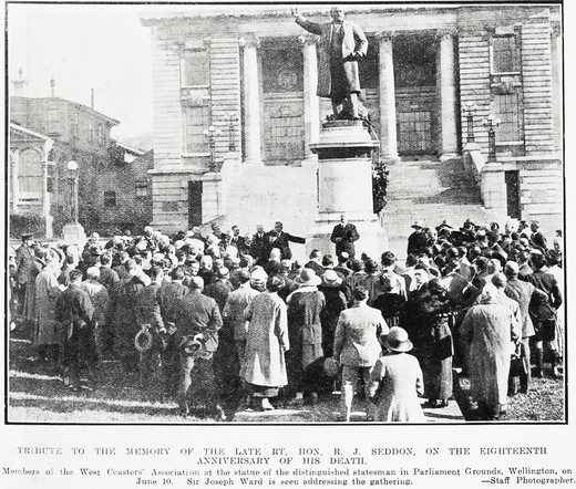 Black-and-white photo: Tribute to the memory of the late Rt. Hon. R. J. Seddon on the eighteenth anniversary of his death. 1924. Extended caption: Members of the West Coasts’ Association at the statue of the distinguished statesman in Parliament Grounds, Wellington on June 10. Sir Joseph Ward is seen addressing the gathering. Description: A view from behind a crowd gathered in front of the statue on a high plinth. The steps leading up to the entrance to Parliament and the entrance itself are in the background. Citation: Auckland Weekly News, 19 June 1924, p. 46. Auckland Libraries Heritage Collections AWNS-19240619-46-02. https://kura.aucklandlibraries.govt.nz/digital/collection/photos/id/246643
