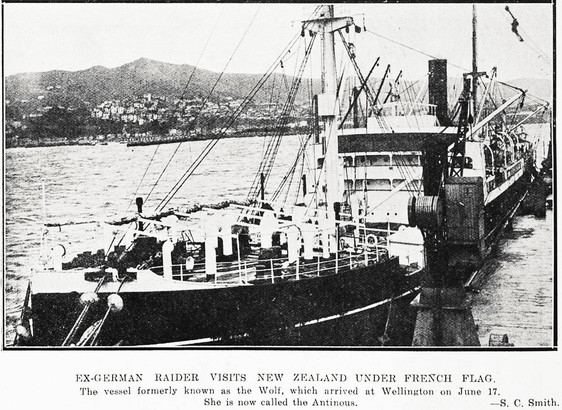 Black-and-white photo: Ex-German raider visits New Zealand under French flag. 1924. Photographer, S. C. Smith. Extended caption: The vessel formerly known as the “Wolf”, which arrived in Wellington on June 17, 1924. She is now called “Antinous”. Description: A front-on, portside view of the vessel docked at a wharf in Wellington harbour; in the background is the harbour, the city centre (half obscured by the vessel) and the slopes of Mount Victoria. Citation: Auckland Weekly News, 26 June 1924, p. 42. Auckland Libraries Heritage Collections AWNS-19240626-42-06. https://kura.aucklandlibraries.govt.nz/digital/collection/photos/id/246501
