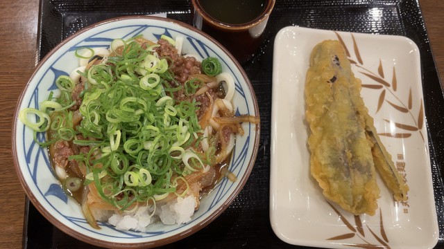丸亀製麺の刻みネギたっぷりのせた鬼おろし肉ぶっかけと大きなナスの天ぷら。