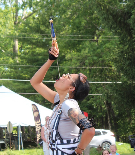 A young lady swallows a sword at an outdoor festival.