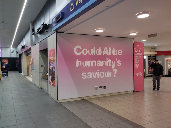 A large advert in Leeds train station - white text on a pink background asking 