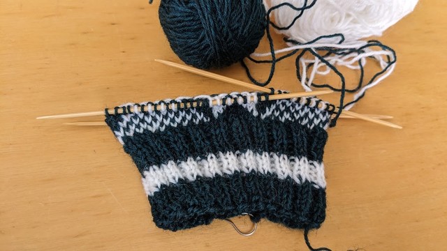 Images of knitting with bar stitches. Dark green and white yarn knitted on 4 needles.