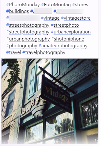 A long list of descriptive hashtags (3 I blurred due to location) with a photo of a store front, with a hard to read sign and some windows showing vintage items.