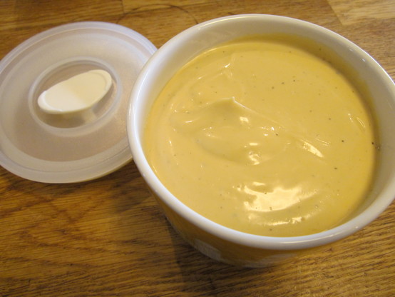 A ceramic stocker with freshly made mayonnaise, with a plastic lid beside it