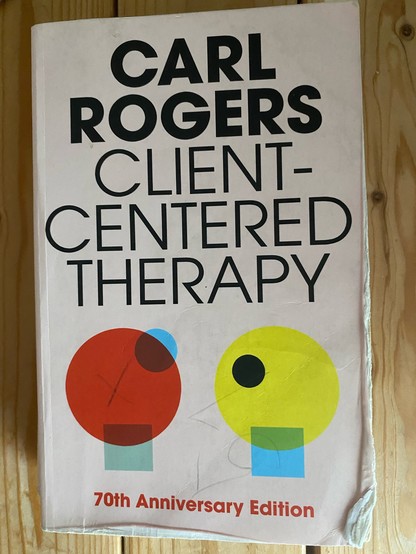 Cover of Client-Centered Therapy by Carl Rogers. 70th Anniversary Edition. Cover art shows abstract circles and rectangles that form two people facing each other 