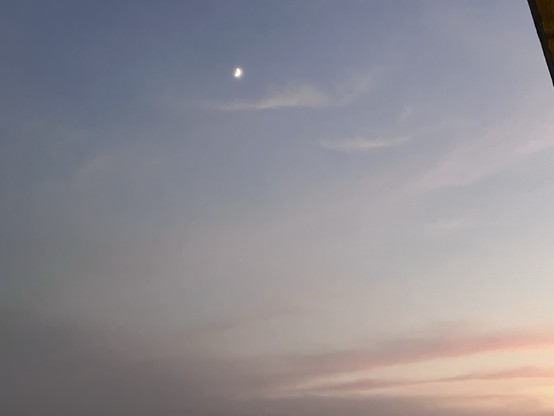 A crescent moon in a pastel-colored twilight sky.