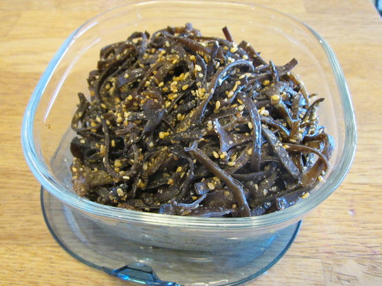 Close up on a glass stocker with shredded kikurage mushroom stir fry with white sesame seeds