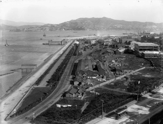 Black-and-white photo: Thorndon, Wellington. 1910. Photographer, Sydney Charles Smith. Description: In the centre are the railway yards. Also visible are Thorndon Esplanade and Thorndon Baths in the middle distance with four domes, one on each corner. In the distance is the harbour and Mount Victoria in the background. Citation: Smith, Sydney Charles, 1888-1972: Photographs of New Zealand. Ref: 1/1-019977-G. Alexander Turnbull Library, Wellington, New Zealand. https://natlib.govt.nz/records/22657666