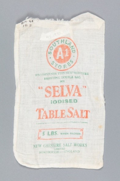 Colour photo: Bag, 5lb Selva Iodised Table Salt. Manufactured 1930s. Description: A white bag with red and green printing. It was manufactured by the New Cheshire Salt Works in Northwich, England, and sold in Southland A1 Stores. The bag was probably imported before the establishment of New Zealand salt works in the 1940s. Background: Before the 1920s, many New Zealanders suffered from goitre as a result of iodine deficiency. This deficiency also caused mental disabilities in young children. In 1924, the New Zealand government established an initiative to add iodine to table salt. This public health action virtually eradicated goitre by the 1950s. Citation: Wyndham and District Historical Museum, Object No. WY.1990.153.6.  https://ehive.com/collections/3102/objects/996257/bag-5lb-selva-iodised-table-salt